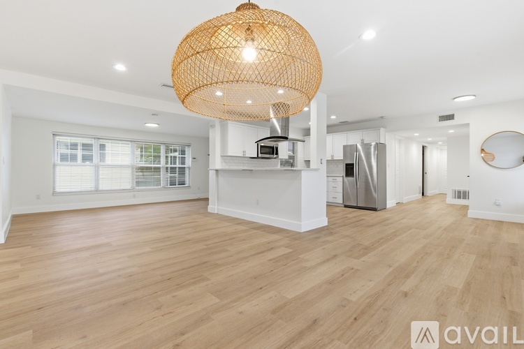 A large open space with wooden floors and a woven light fixture.