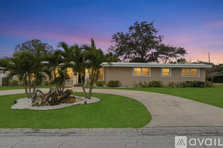 A house with a front yard and palm trees.