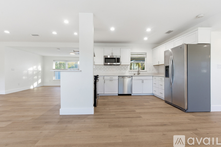 A kitchen with white cabinets and a wooden floor.