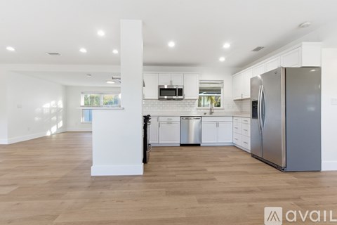 A kitchen with white cabinets and a wooden floor.
