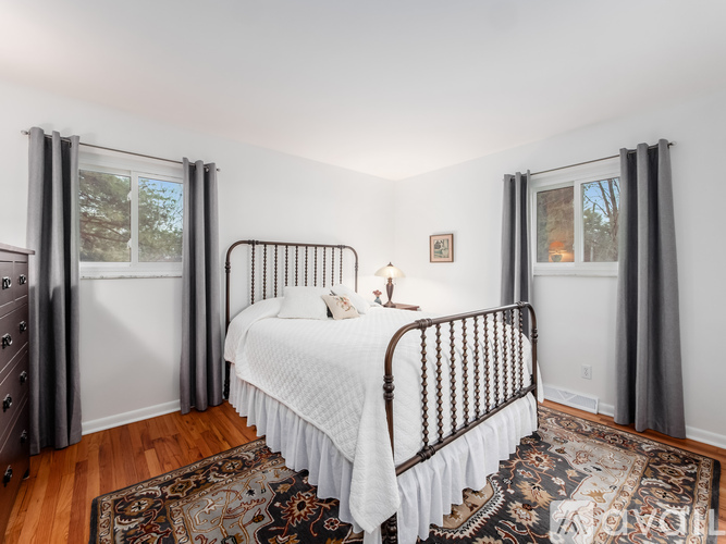 A bedroom with a white bed and a patterned rug.