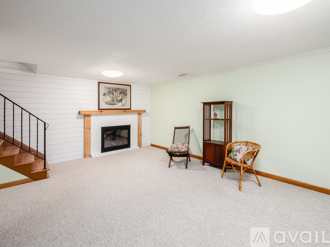 A living room with a fireplace, two chairs, and a painting on the wall.