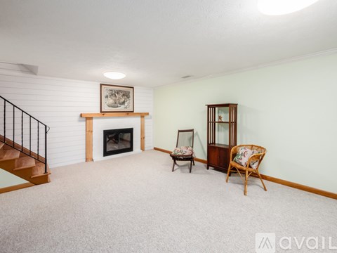 A living room with a fireplace, two chairs, and a painting on the wall.
