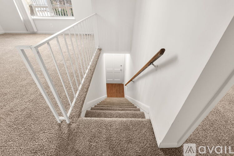 A staircase with a carpeted runner and a wooden handrail.