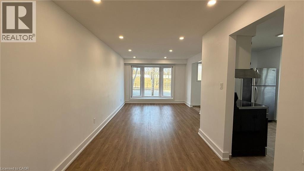 A spacious room with wooden flooring and a large window.