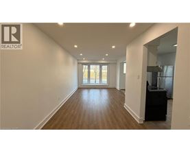 A spacious room with wooden flooring and a large window.