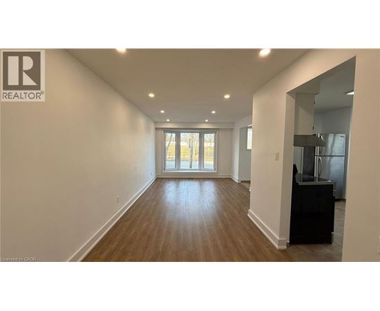A spacious room with wooden flooring and a large window.