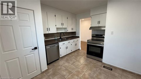 A kitchen with white cabinets and a tiled floor.