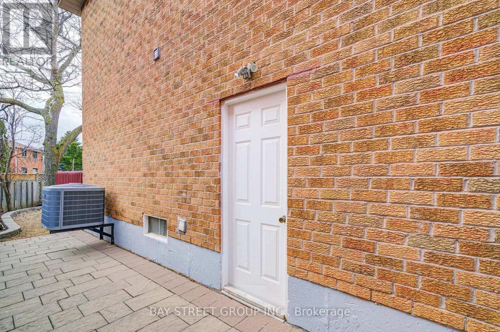 A red brick wall with a white door and a small window.