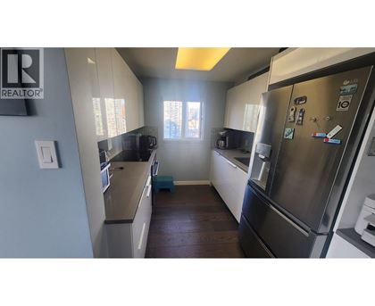 A kitchen with a refrigerator on the right and a counter on the left.