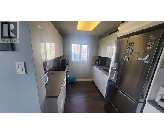 A kitchen with a refrigerator on the right and a counter on the left.