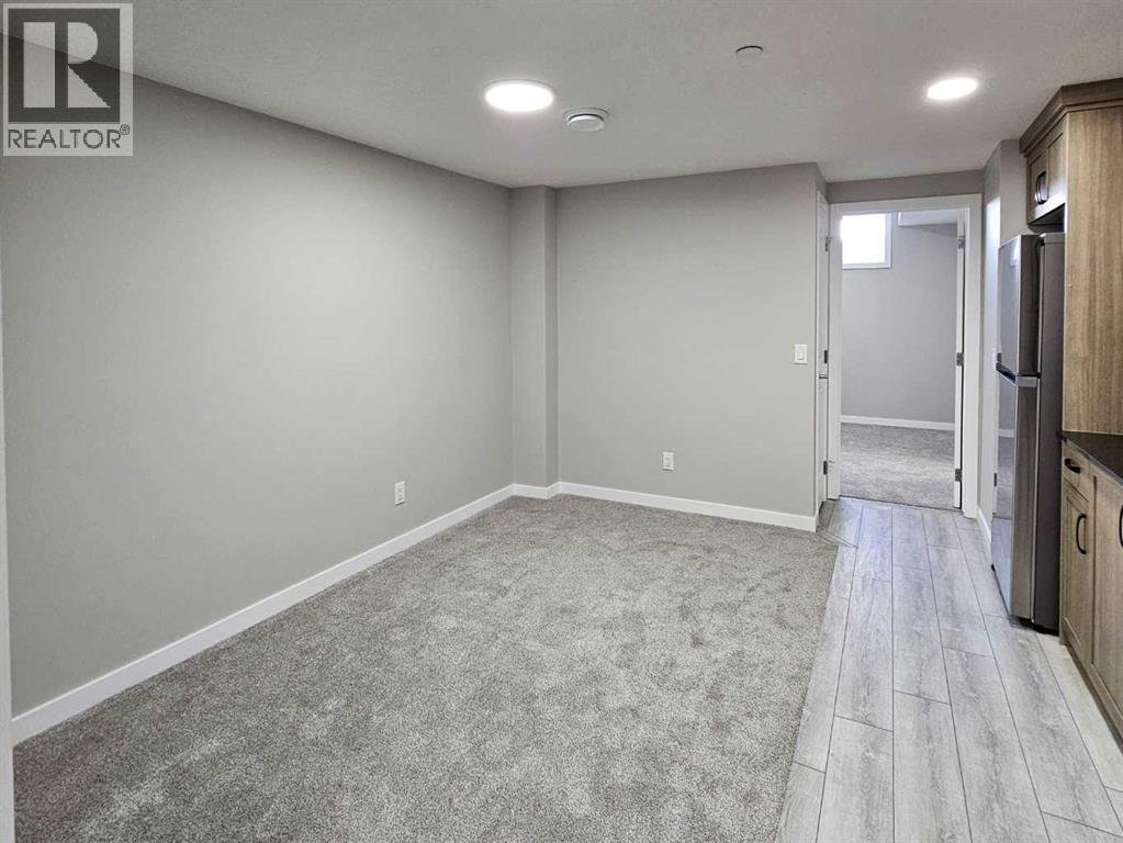 A spacious room with grey carpeting and wooden flooring.