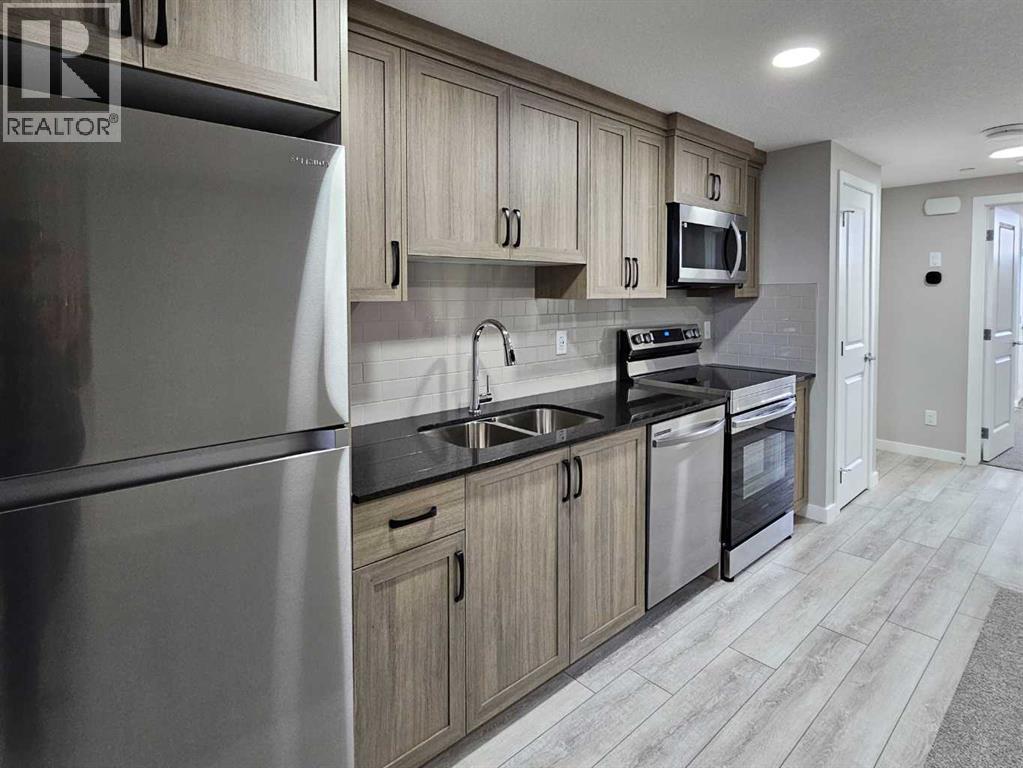 A kitchen with a stainless steel refrigerator, microwave, and oven.