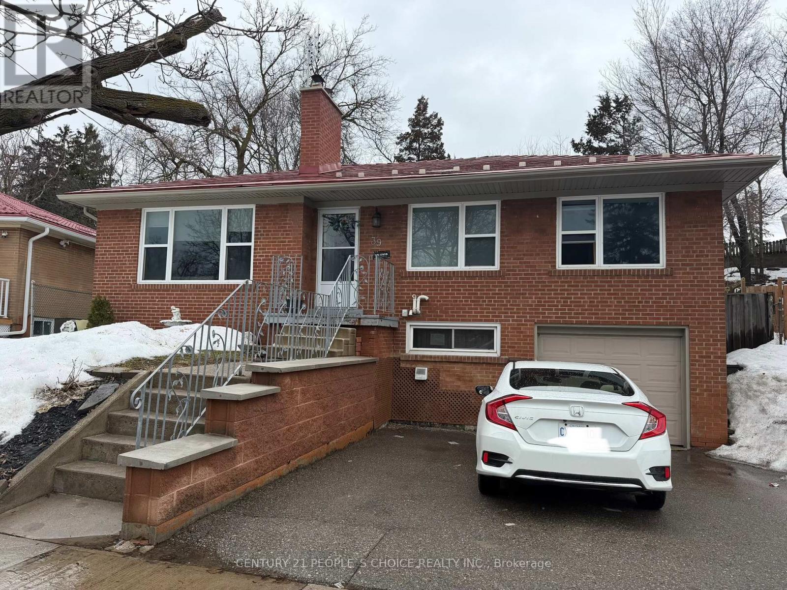 A white car is parked in front of a brick house.