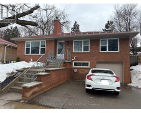 A white car is parked in front of a brick house.
