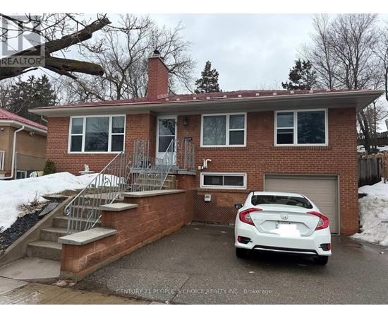 A white car is parked in front of a brick house.