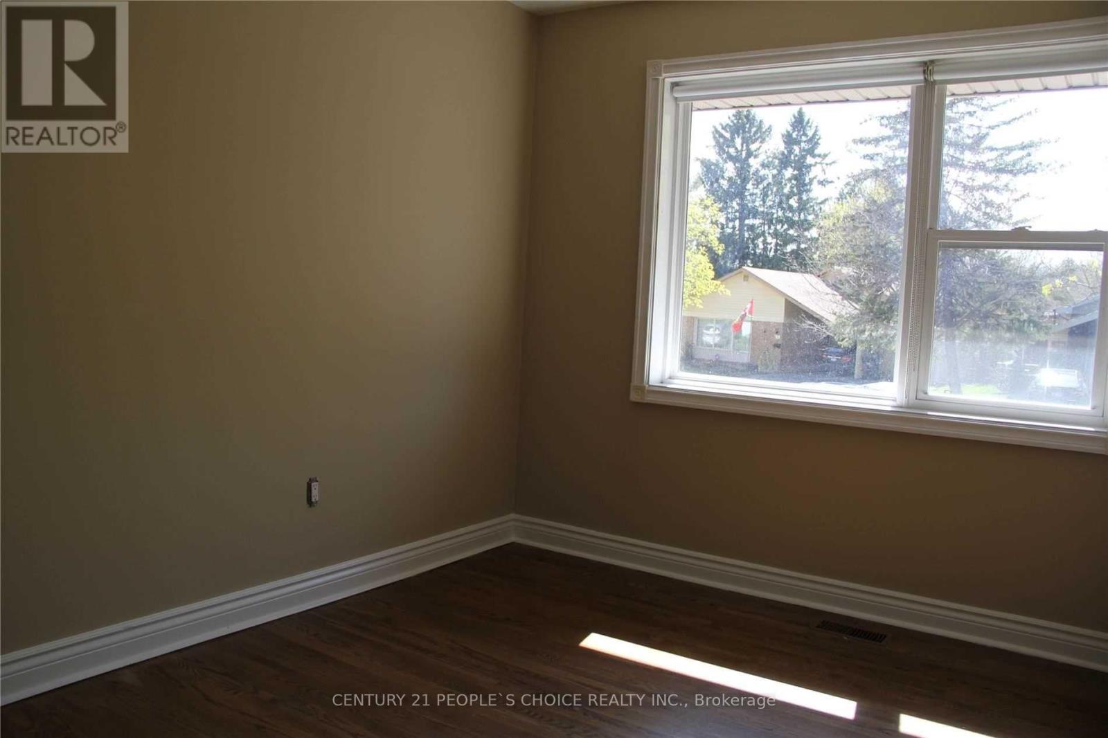 A room with a window showing trees and houses outside.