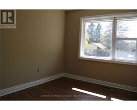 A room with a window showing trees and houses outside.