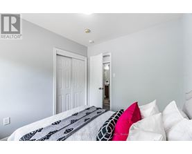 A bedroom with a bed and pillows in the foreground and a doorway in the background.