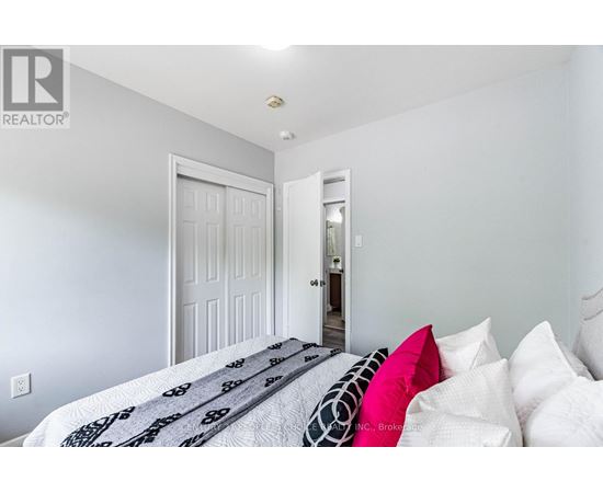 A bedroom with a bed and pillows in the foreground and a doorway in the background.
