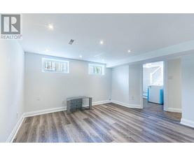 A spacious room with wooden flooring and white walls.