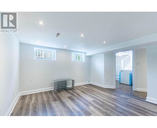 A spacious room with wooden flooring and white walls.