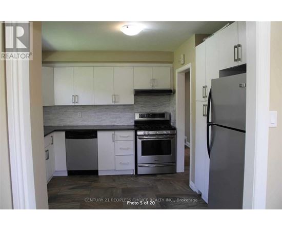 A kitchen with white cabinets and a grey refrigerator.