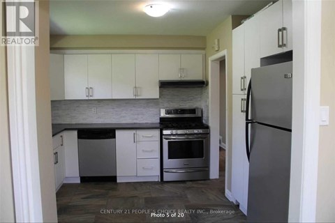 A kitchen with white cabinets and a grey refrigerator.