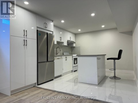 A modern kitchen with white cabinets and a stainless steel refrigerator.