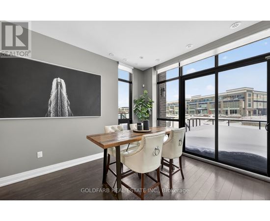 A dining room with a wooden table and chairs, a large window, and a painting on the wall.