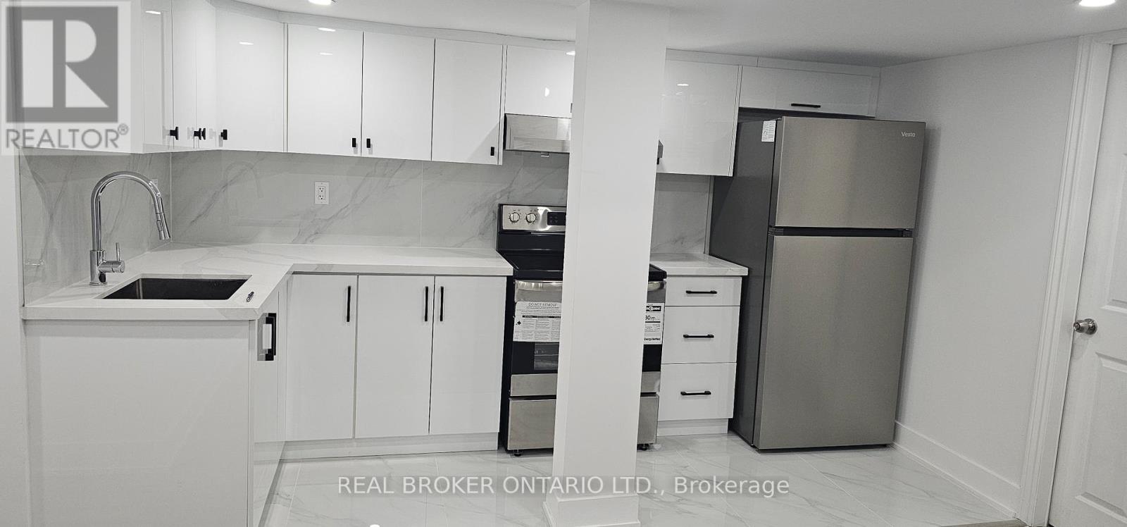 A kitchen with white cabinets and a refrigerator.