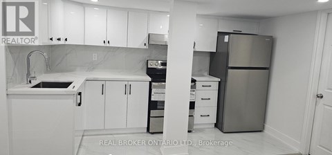 A kitchen with white cabinets and a refrigerator.
