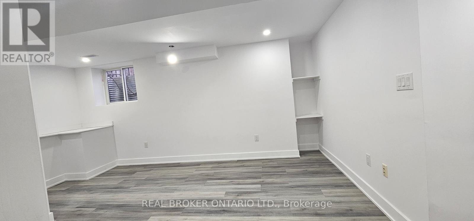 A spacious room with a window and a shelf is available for rent.