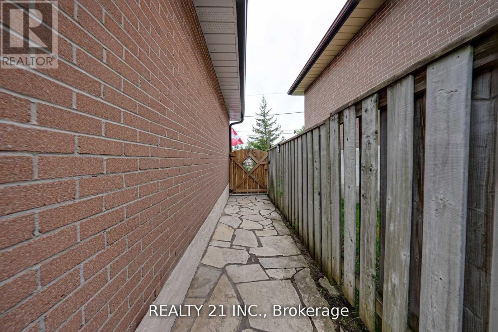 A brick wall with a wooden fence and a stone pathway.