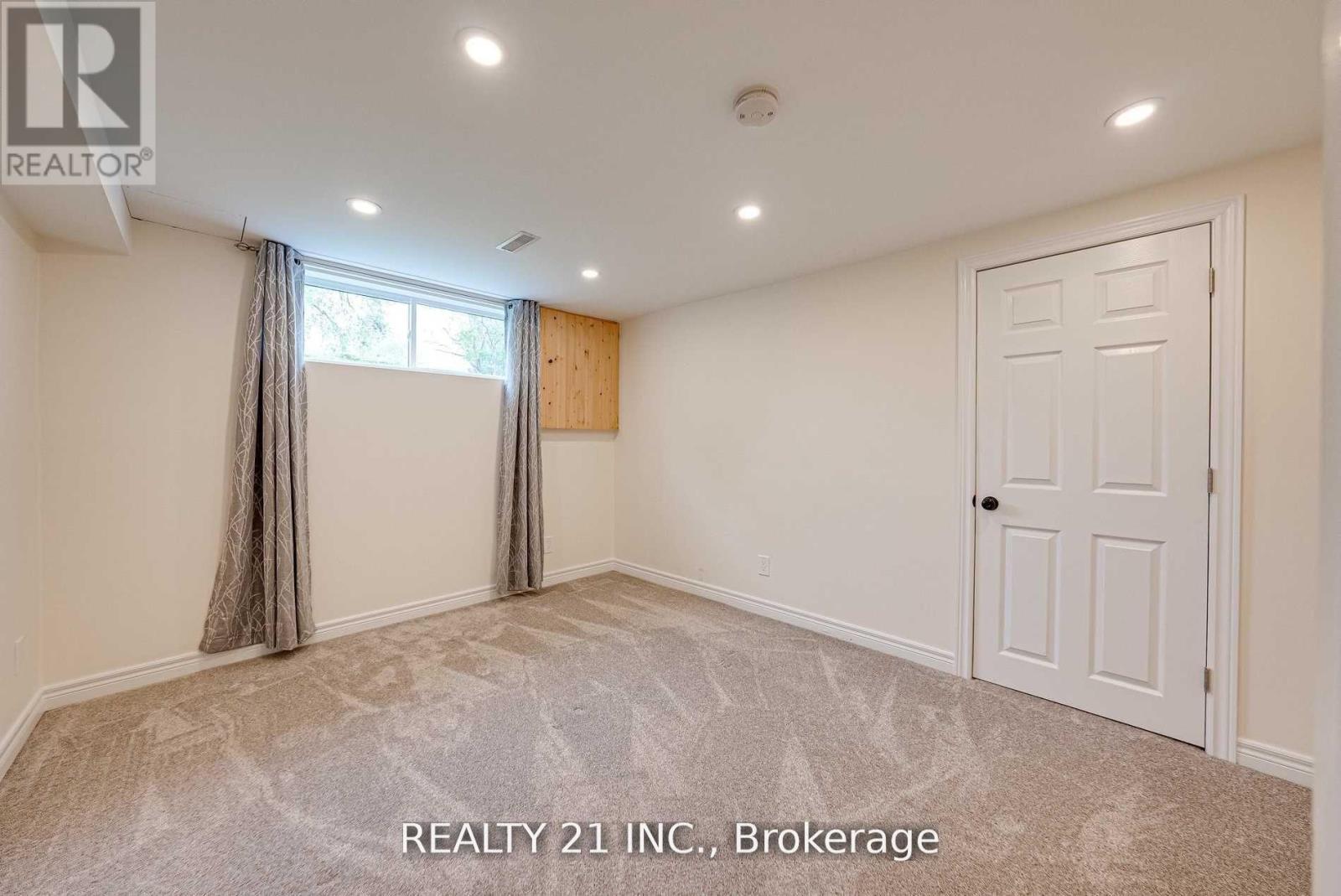A room with a carpeted floor, a window with curtains, and a door.