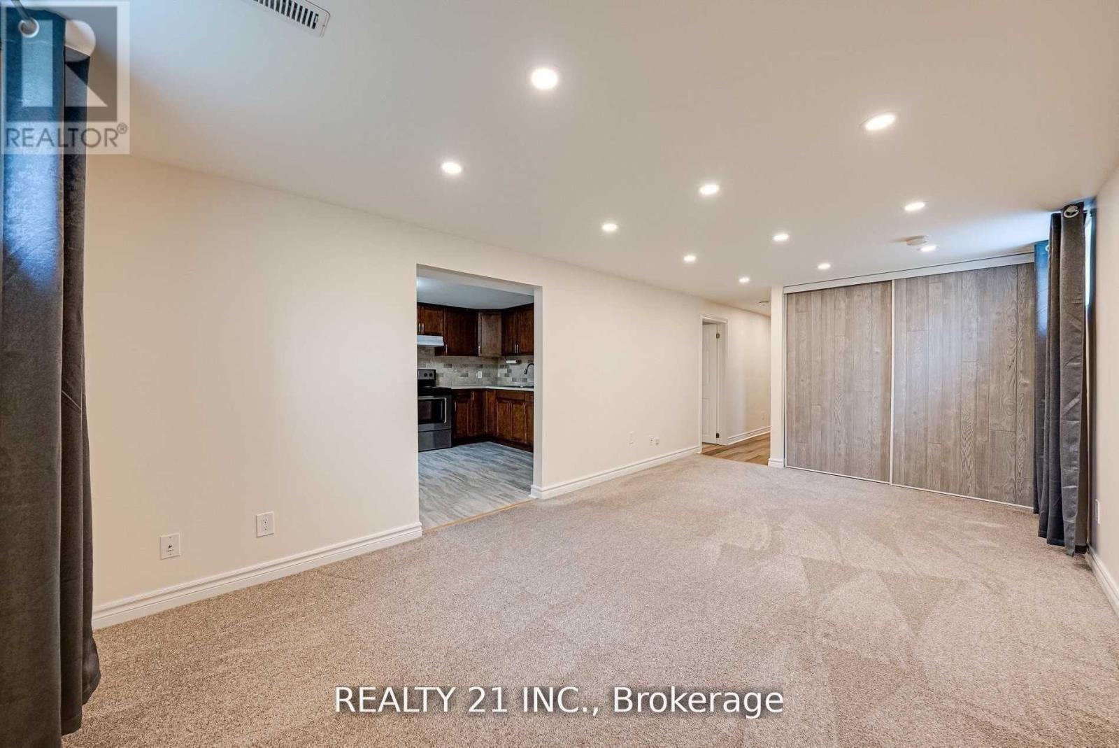 A spacious room with a carpeted floor and a ceiling with recessed lighting.
