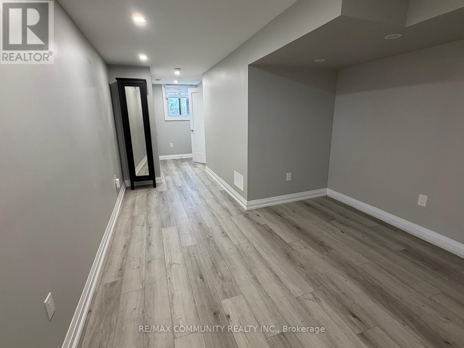 A spacious room with wood flooring and a large mirror on the wall.