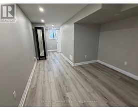 A spacious room with wood flooring and a large mirror on the wall.