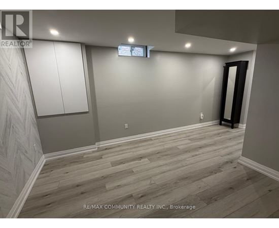 A room with wooden flooring and a wall with a herringbone pattern.