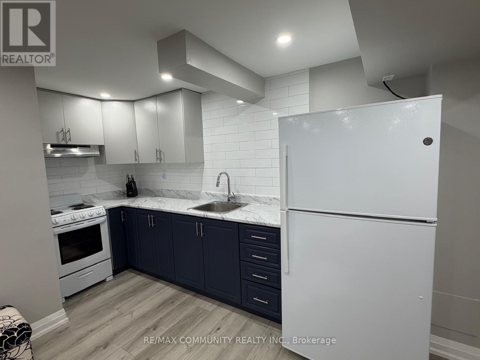 A kitchen with white appliances and dark blue cabinets.