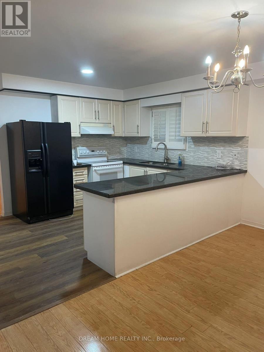 A kitchen with a black fridge and wooden floors.