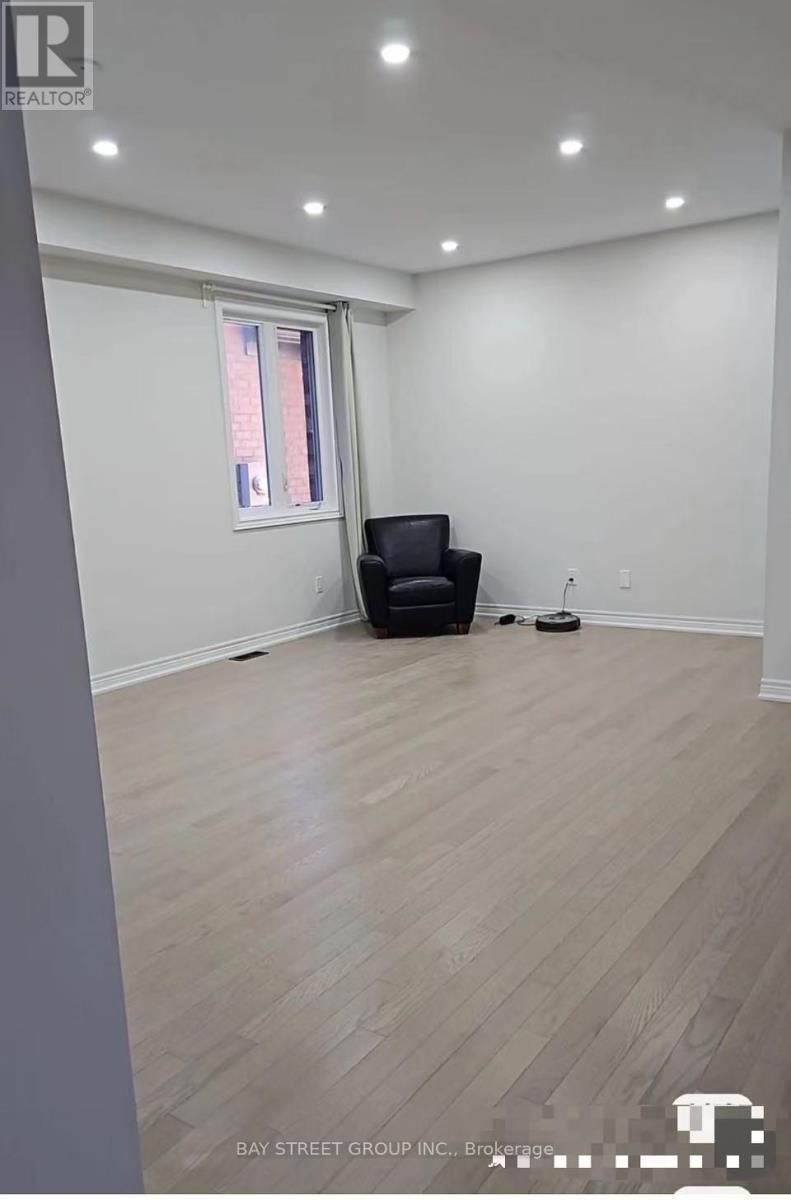 A spacious room with a black chair and wooden flooring.