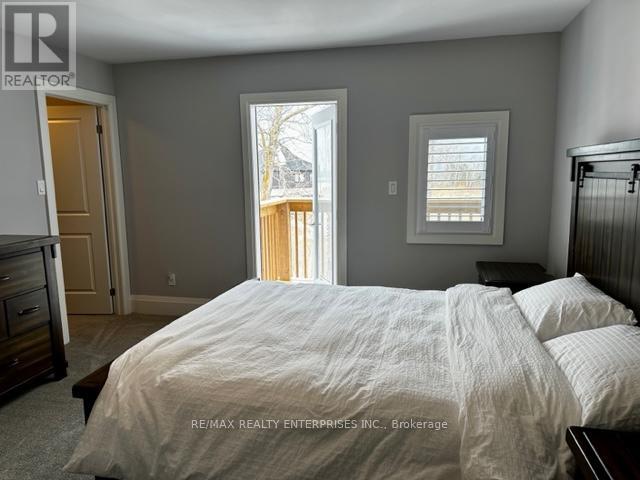A bedroom with a large bed and a view of a deck outside the window.