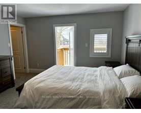 A bedroom with a large bed and a view of a deck outside the window.