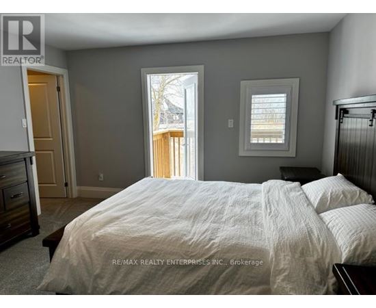 A bedroom with a large bed and a view of a deck outside the window.