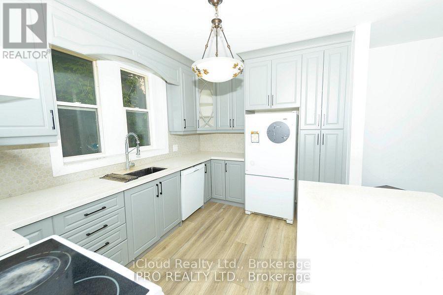 A kitchen with white cabinets and a white fridge.