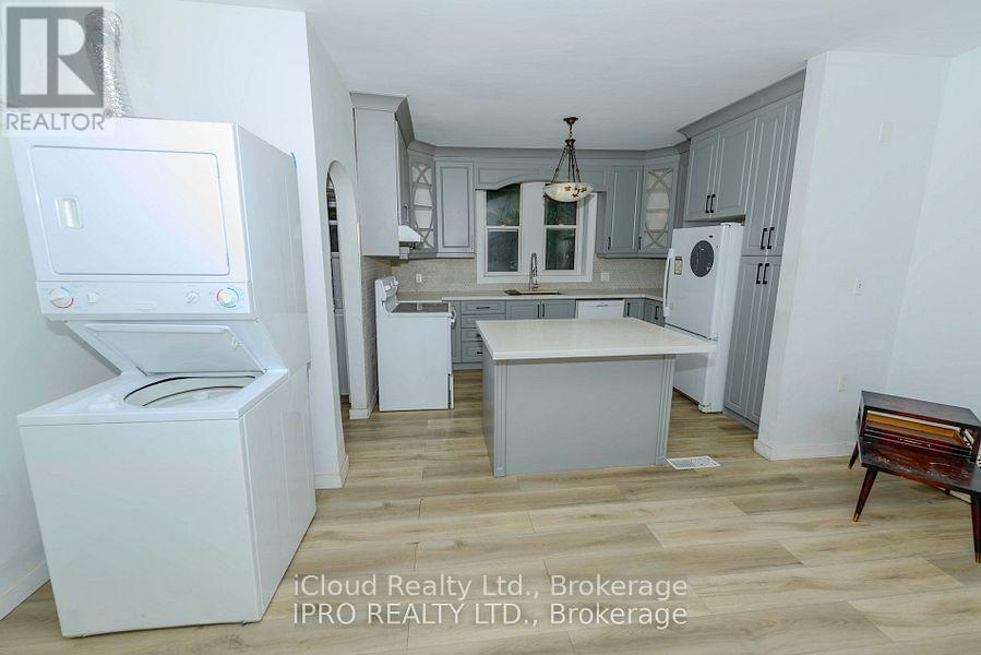 A kitchen with white appliances and wooden floors.