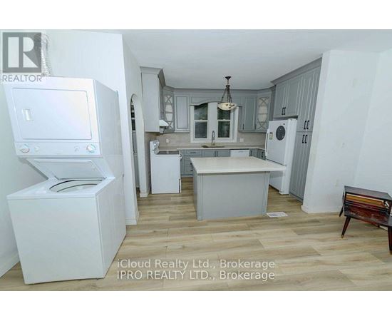 A kitchen with white appliances and wooden floors.