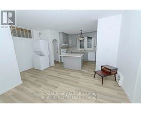 A kitchen with a refrigerator, sink, and cabinets.