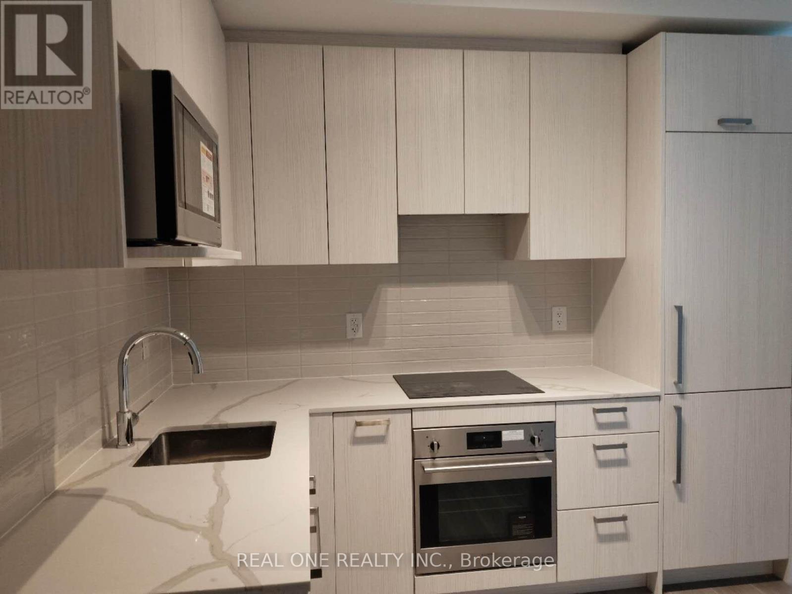 A kitchen with white cabinets and a black microwave.